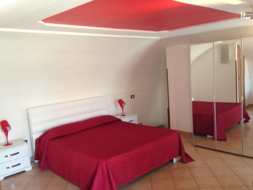 um quarto com uma cama vermelha e um espelho em Villa Bebe' em Vico Equense