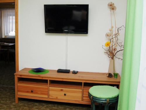SaupsdorfにあるSiebers-Ferienwohnungの木製ドレッサー(緑の椅子付)と壁掛けテレビ付