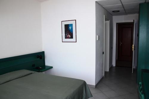 a bedroom with a green bed and a hallway at Hotel Miralonga in La Maddalena