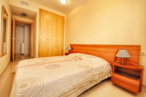 Un dormitorio con una cama grande y una mesa con una lámpara. en Apartamento ADIA, en Lloret de Mar