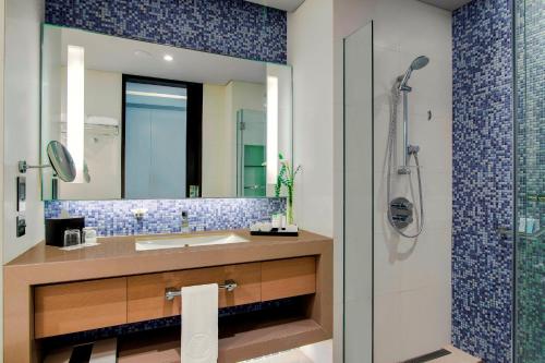 a bathroom with a sink and a shower with a mirror at Capital Centre Arjaan by Rotana in Abu Dhabi