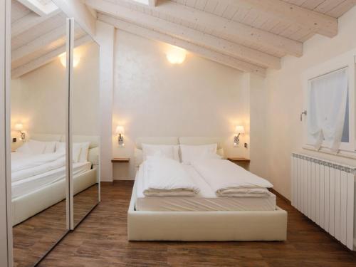 a white bedroom with a large white bed and a mirror at Les Suites in Asola