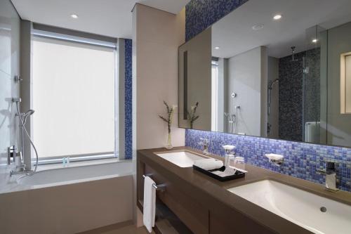 a bathroom with a tub and a sink and a mirror at Capital Centre Arjaan by Rotana in Abu Dhabi