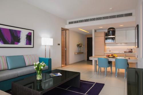 a living room and kitchen with a couch and a table at Capital Centre Arjaan by Rotana in Abu Dhabi