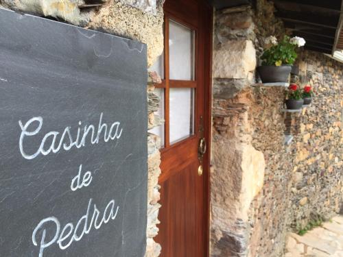 a sign in front of a building with a door at Casinha de Pedra in Penacova