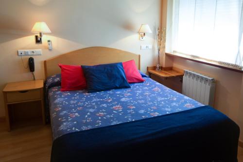 a bedroom with a bed with two colorful pillows at Hotel Villa de Ayerbe in Ayerbe