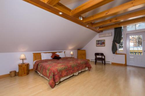 sypialnia z dużym łóżkiem i drewnianą podłogą w obiekcie Aux petits oiseaux CITQO96751 w mieście Baie-Saint-Paul