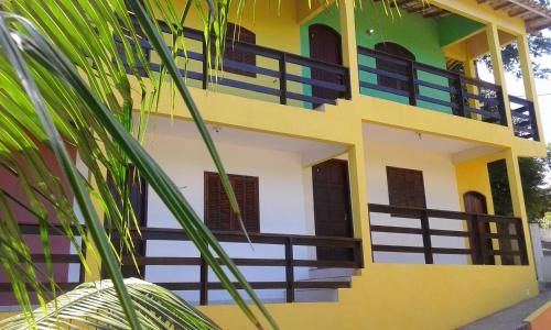 a yellow and white building with a palm tree at Wando Suítes in Búzios