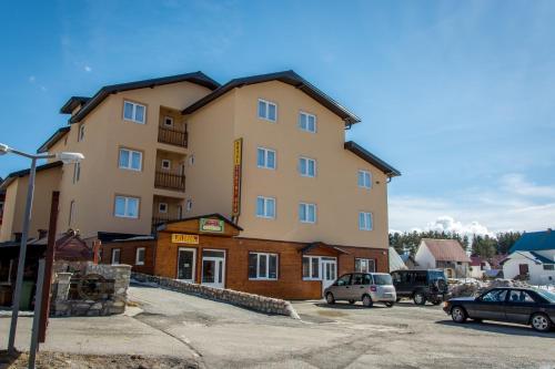 a large building with cars parked in a parking lot at Hotel Zlatni bor in Žabljak