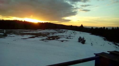 a snow covered hill with the sun setting in the background at Chalet Mechka in Borovets