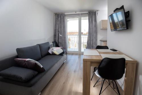 a living room with a couch and a desk at 100-SIO Apartamenty Budget I in Koszalin