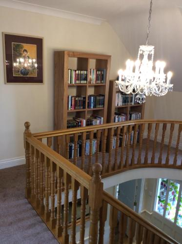 a staircase with a chandelier and a book shelf with books at Edencrest B&B in Bantry