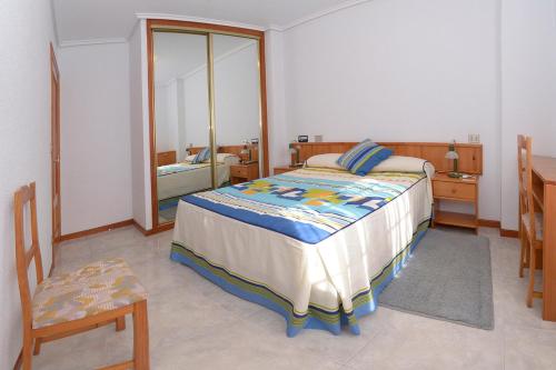 a bedroom with a bed and a chair and a mirror at Apartamentos La Terraza in Laredo