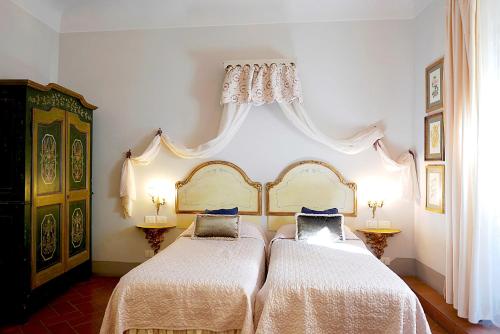 a bedroom with two beds with white sheets and blue pillows at Relais Cavalcanti Guest House in Florence