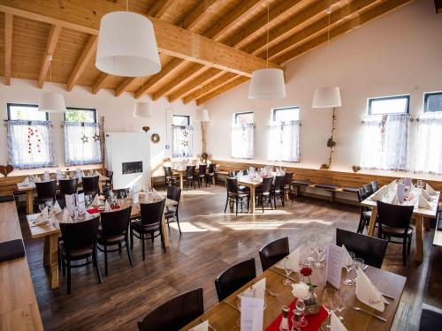 a dining room with tables and chairs and windows at Schlemmerhütte - Hotel in Langweid