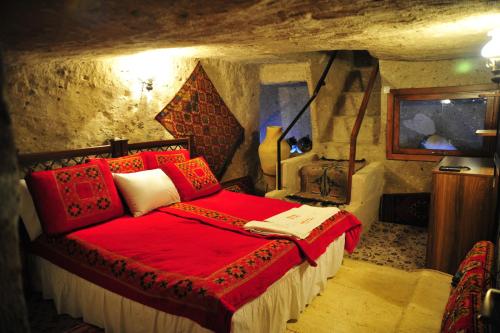 a bedroom with a red bed in a cave at Osmanoglu Hotel in Guzelyurt