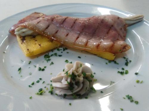 a piece of meat on a white plate with onions at Hotel Ristorante Stella in Palestrina
