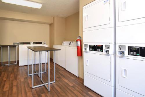 a room with white appliances and a table with a fire extinguisher at Extended Stay America Suites - Dallas - Coit Road in Dallas