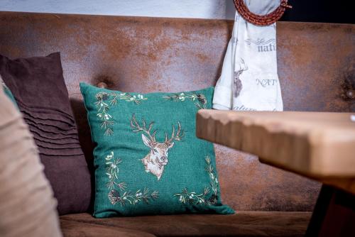 a green pillow with a deer on it sitting on a couch at Haus Mösenlechner in Maishofen