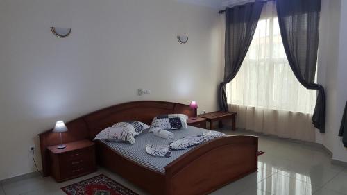 1 dormitorio con cama con almohadas y ventana en Résidence hôtelière La Roseline en Yaundé