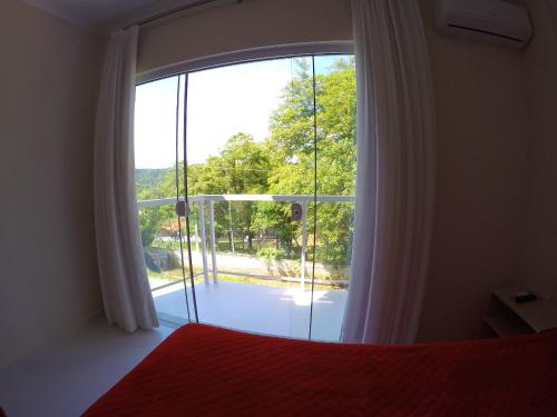 a bedroom with a bed and a large window at Pousada Magnus in Balneário Camboriú