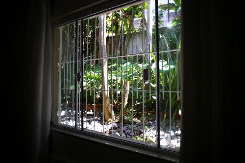 a window with a view of a garden outside at Pousada Magnus in Balneário Camboriú
