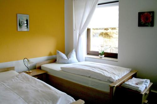 two beds in a room with a window at Berghotel Steiger - Pfotenurlaub in Schneeberg