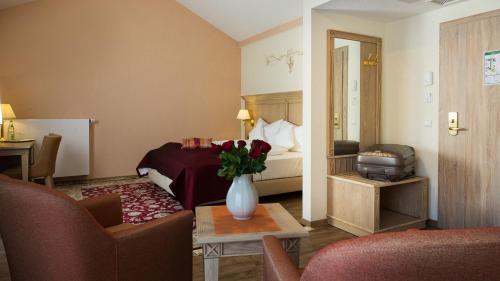 a hotel room with a bed and a vase of flowers at Hotel Rebstock in Baden-Baden