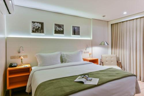 a hotel room with a bed with a book on it at Intercity Anápolis in Anápolis