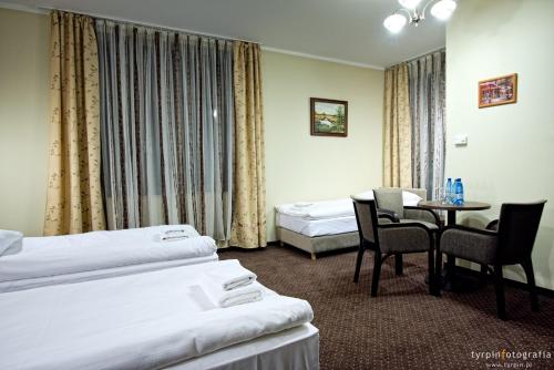 a hotel room with two beds and a table and chairs at Hotel Lord Krosno in Krosno