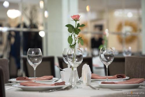 a table with wine glasses and a rose in a vase at Hotel Lord Krosno in Krosno
