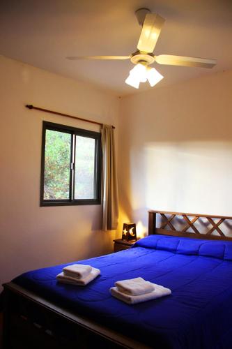 a bedroom with a blue bed with a ceiling fan at Cabañas El Arcano in Capilla del Monte