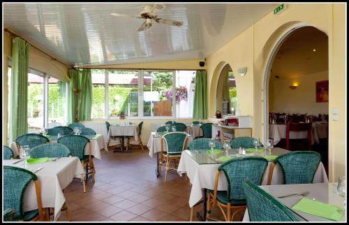 un restaurant avec des tables et des chaises blanches et des fenêtres dans l'établissement Dolce Vita, à Bruay-la-Buissière