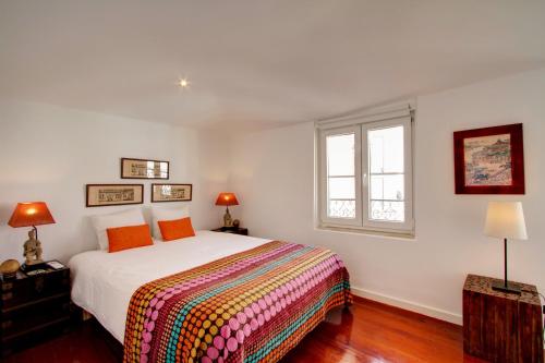 リスボンにあるGreat Duplex Apartment in Alfamaのベッドルーム1室(大型ベッド1台、カラフルな毛布付)