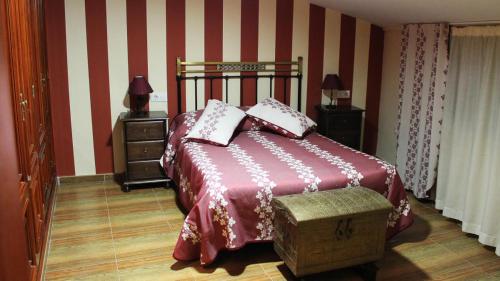 a bedroom with a bed with red and white stripes at La Casa de los Templarios in Puebla de Alcocer