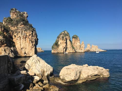 a group of rocks in the water near the ocean at Appartamenti Cala Azzurra in Scopello