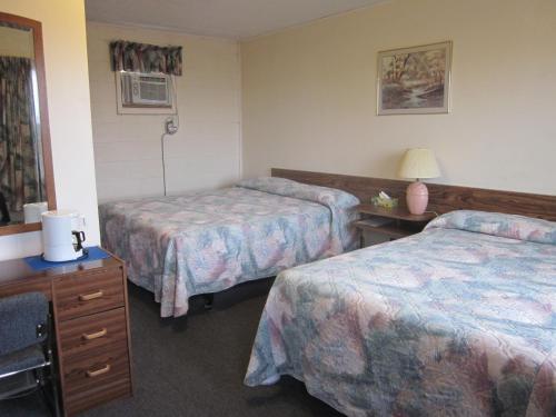 um quarto de hotel com duas camas e uma mesa com um candeeiro em City Centre Motel em Swift Current