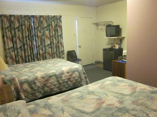 a hotel room with two beds and a television at City Centre Motel in Swift Current