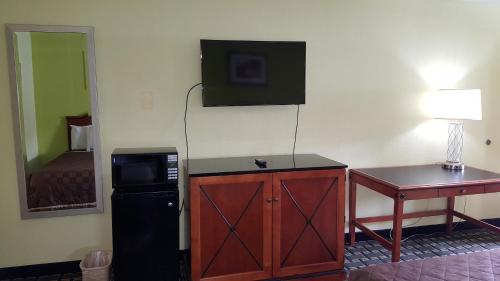a room with a refrigerator and a television on the wall at American Inn Columbia in Columbia