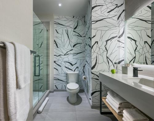 Hotel Zero Degrees Danbury في دانبري: حمام به مرحاض أبيض وورق جدران أبيض وأسود