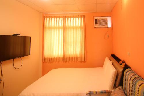 1 dormitorio con paredes de color naranja, 1 cama y TV en Happy Homestay, en Budai