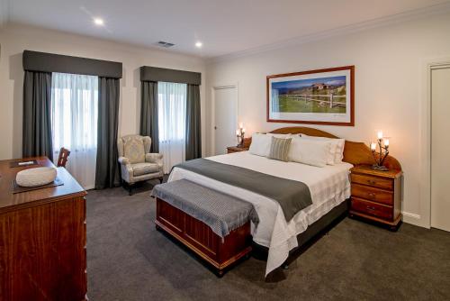 Mount McKenzieにあるBrockenchack Vineyard Bed & Breakfastの大きなベッドと椅子が備わるホテルルームです。