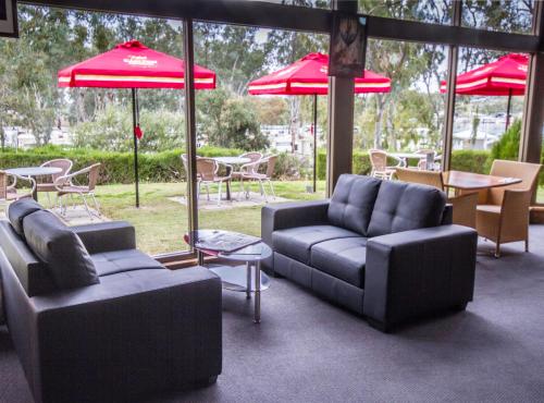 a patio with couches and chairs and tables and umbrellas at Mannum Motel in Mannum