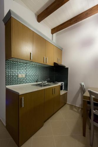 a kitchen with wooden cabinets and a sink and a table at Ideal House in Parga