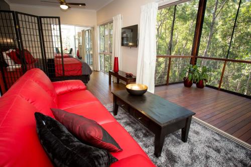 a living room with a red couch and a table at Mt Cotton Retreat in Mount Cotton