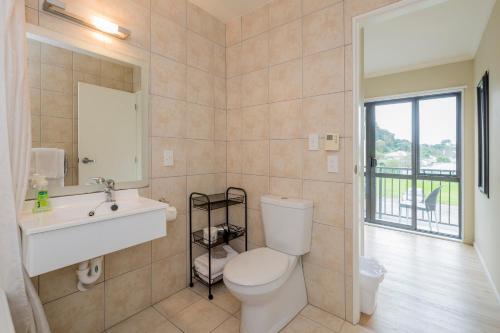 a bathroom with a toilet and a sink and a window at Finns Paekakariki in Paekakariki