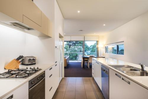 a kitchen with white cabinets and a dining room at Coast Resort Merimbula in Merimbula