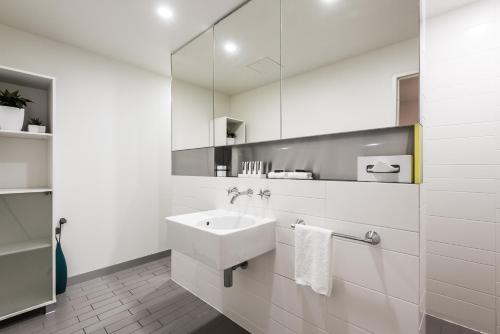 a white bathroom with a sink and a mirror at Coast Resort Merimbula in Merimbula