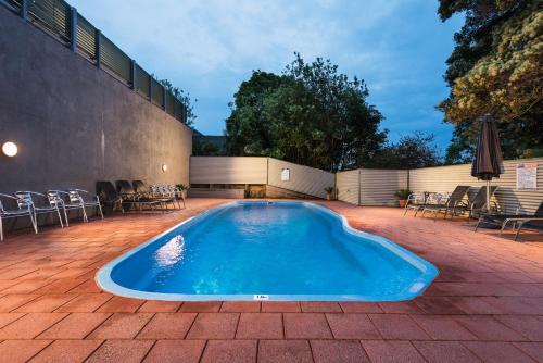 a swimming pool on a patio with tables and chairs at Horizon Holiday Apartments in Narooma