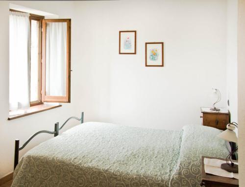 a white bedroom with a bed and two windows at Borgo San Valentino in Arrone